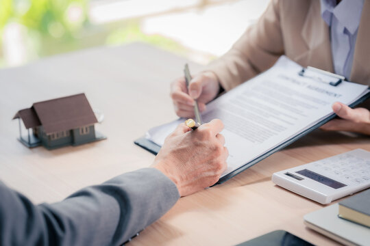 Real estate agent with documents to buy new house of house plan and keys on table. At table with model house. Real estate. Close up.