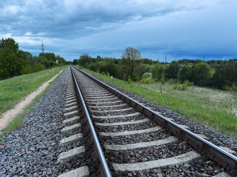 train rail in the nature, forest of green trees, cloudy sky