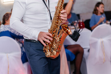 Musician playing a golden saxophone during a wedding celebration, filling the air with joyful melodies and creating an elegant atmosphere for the bride, groom, and guests