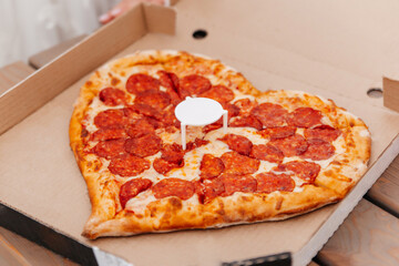 Heart-shaped pizza in a cardboard box close-up. Valentine's Day celebration.