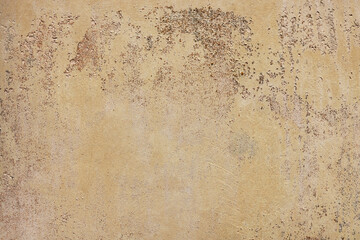 Close-up of aged concrete wall surface with weathered remains of yellow paint. Grunge background with copy space.