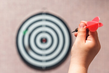 Playing darts, child's hand aiming a dart at a target