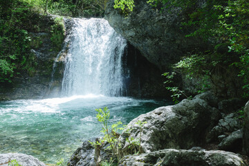 Olympus, surrounded by rocky cliffs and dense green forest vegetation.
