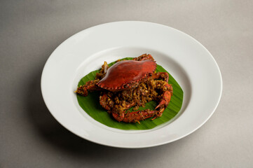 Cooked Crab with Mild Spices and Velouté Sauce Served on Banana Leaf in White Plate – Gourmet Seafood Presentation on Grey Background