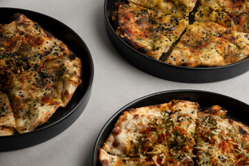 Partial Overhead View of Stuffed Veg Kulcha, Chicken Tikka Kulcha, and Chorizo Kulcha – Trio of Indian Fusion Flatbreads on Grey Background