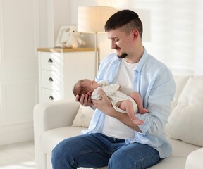 Father with his cute newborn baby on sofa indoors