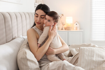 Bedtime. Mother with her cute little baby on bed at home