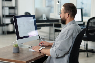 Technician making digital engineering drawing on computer at desk in office