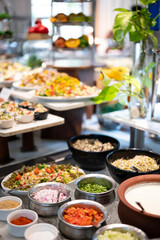 Freshly served raita with neatly cut vegetables at a buffet counter, with a variety of vibrant salads softly blurred in the background for a colorful, appetizing display.
