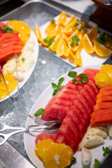 Close-up of a vibrant fruit salad plate at a buffet counter, featuring freshly cut watermelon, pineapple, and oranges arranged for a refreshing and healthy dining experience.