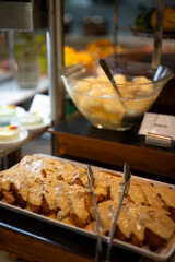 Rich and creamy Indian malai rabri served at a dessert buffet counter, with soft white rasgullas blurred in the background for a traditional festive presentation.
