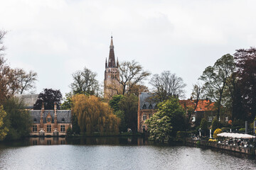 view of the old town of brugge in belgium, and its canals, on a spring day. vloudy light and tower view