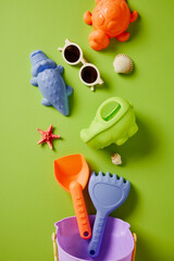 Plastic sand toys set: bucket, spade, rake, and sea creatures on green background.