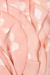 Fototapeta premium A close-up shot reveals the delicate, overlapping slices of mortadella, showcasing its pale pink color and characteristic white fat inclusions