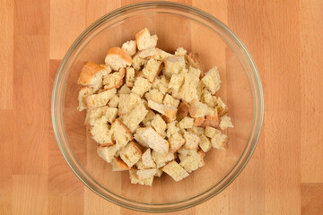 This image shows a glass bowl full of diced stale bread, ready for making bread dumplings placed on...
