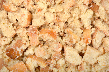 A detailed close-up shows a mixture of irregularly shaped pieces of stale bread, moistened and...