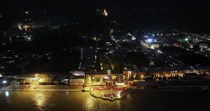 Aerial Drone Shot of Ganga Aarti at Rishikesh Ghat in Evening Light Revealing River, Temples and Illuminated Cityscape