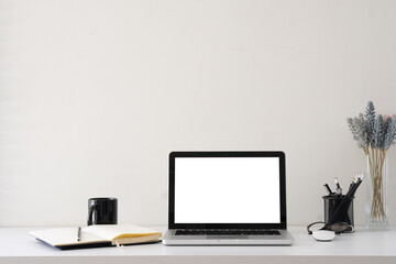 Modern workstation with laptop featuring a blank screen, and mug for business or creative concepts.