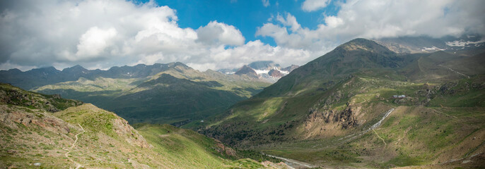 Panoramic mountain view with meadow and clouds