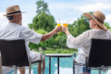happy senior couple enjoy talking with freshy drink on table,sitting,relaxing by the pool,elderly...