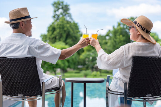 happy senior couple enjoy talking with freshy drink on table,sitting,relaxing by the pool,elderly people travel destination tropical resort and spa on summertime - Powered by Adobe
