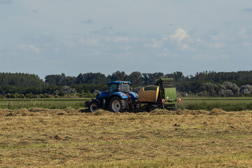 Tractor harvesting hay in rural field
