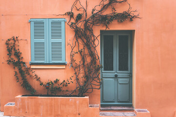 old closed window and door with green shutters on a peach colour house in saint tropez, cote d'azul