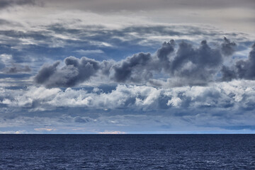 A dramatic stormy sky looms over the vast expanse of Lake Titicaca, casting deep shadows and rich blues across the high-altitude landscape.