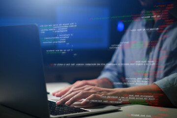 Hands typing on laptop with programming code on screen, representing software development. Perfect...