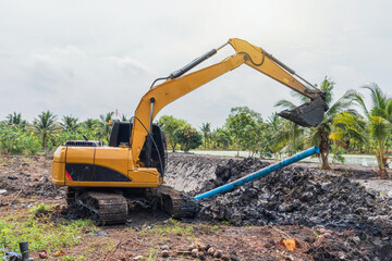 Construction work to adjust the area for agriculture. Excavator is working to lift blue pipes. pipe laying and trench digging work in cultivation areas in lowlands Thailand.
