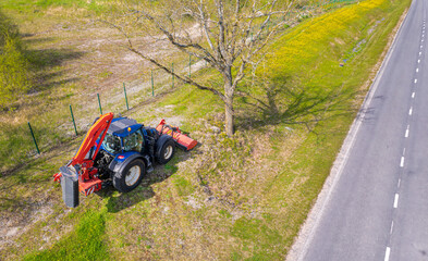 blue tractor mowing grass on the side of the road