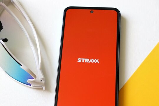 Bahia, Brazil - May 22, 2025: Strava app on smartphone screen and running sunglasses. Strava is a popular fitness tracking app for runners, cyclists, and other athletes.