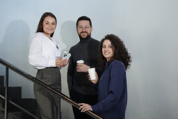 Colleagues with coffee on stairs in office during break