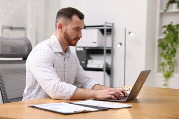 Fototapeta premium Man working on laptop at desk in office