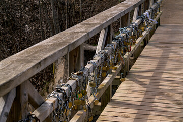 Old wooden bridge with iron locks on the fence, early spring.