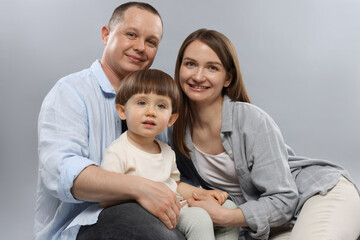Happy parents and their baby boy on light grey background. Lovely family