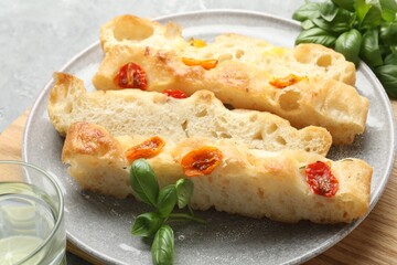Pieces of delicious focaccia with tomatoes and basil on gray table, closeup