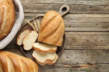 Cut bread loaf and spikes on wooden table, flat lay. Space for text