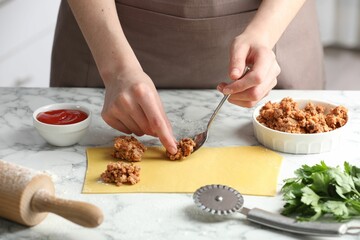 Woman making ravioli bolognese at white marble table, closeup