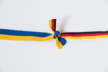 Flag of Ukraine and Germany tied in a knot on a white background, a symbol of friendship and...