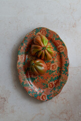 Heirloom tomatoes on a decorative floral plate, great for home decor projects. Use in kitchen styling, interior design blogs or table setting. Enhance your space with this vintage-inspired food scene.