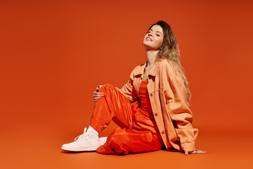 A stylish young woman lights up the scene in a vibrant orange outfit