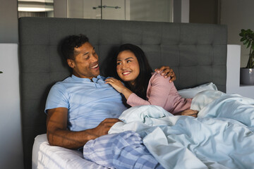 Couple relaxing in bed, smiling and enjoying morning together at home