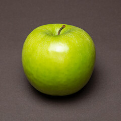 Fresh green apple resting on dark surface showcasing its vibrant color and smooth texture under soft lighting