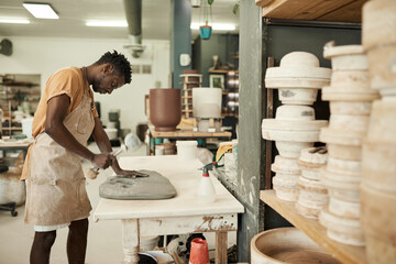 Young African ceramist hitting a piece of clay with a mallet