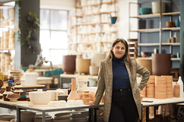 Smiling young ceramics workshop owner standing next to a studio bench