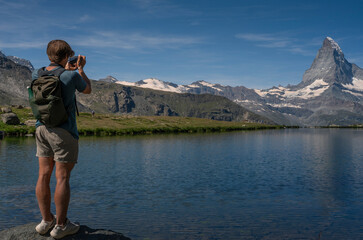Boy taking pictures of the Stellisee lake in front of the Matterhorn, Switzerland