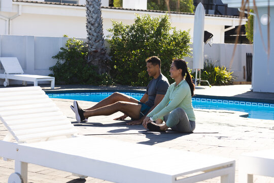 Couple practicing yoga by poolside, enjoying peaceful morning exercise together