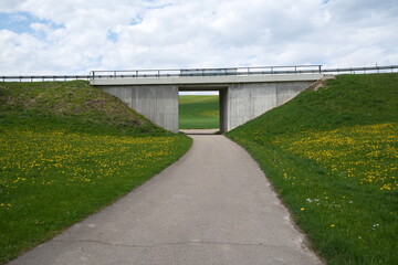 Feldweg unter Straßenbrücke – Übergang von Natur und Infrastruktur im Frühling