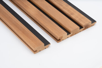 Brown acoustic wood slats with black felt backing and tongue-and-groove edges, arranged on a white...